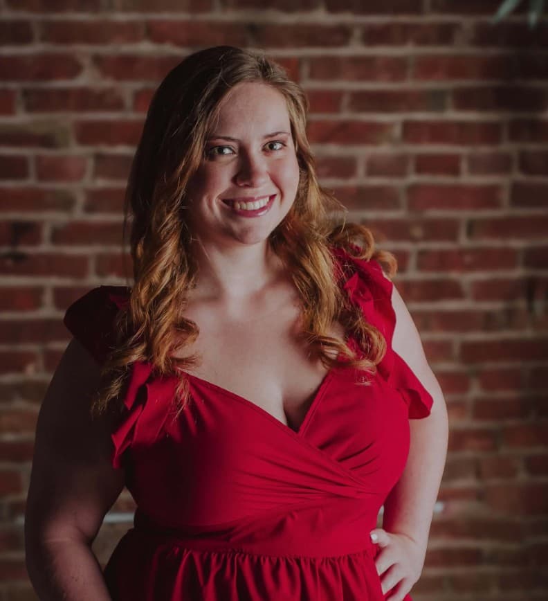 ReAnna Sperle, founder of Sperle Bookkeeping LLC, smiling in a red dress against a brick wall